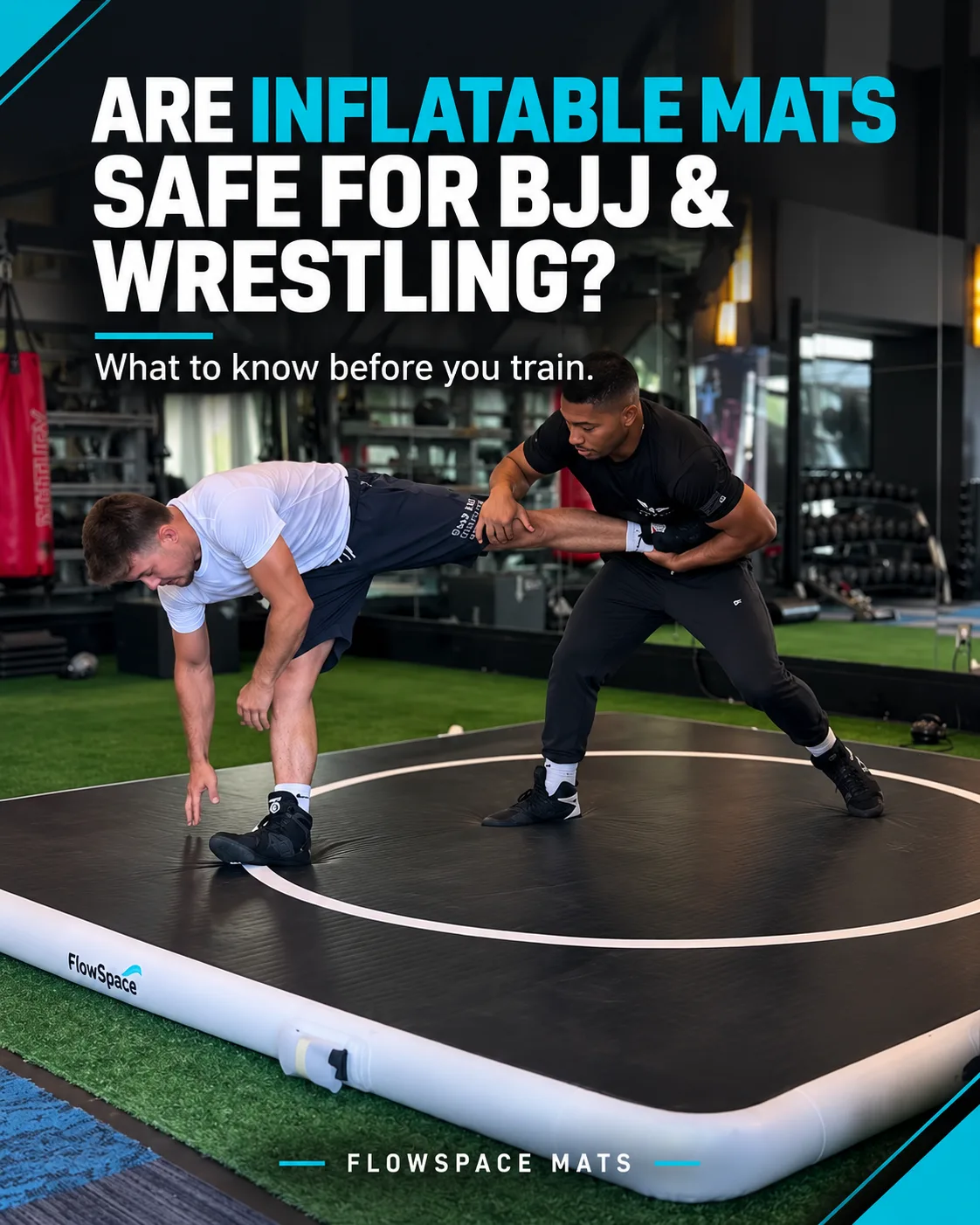 Two athletes drilling a takedown on a black FlowSpace inflatable mat with a white competition circle, set up on turf in a gym.
