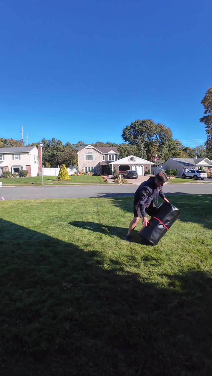 Lifting the rolled mat, cinched with a red strap, to stand it up for the duffle bag
