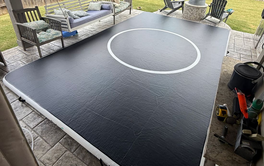 A 10 by 15 Pro FlowMat filling a covered back patio, with a garden swing and lawn behind it